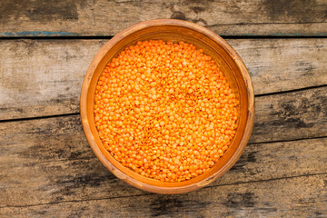 Raw lentil in bowl on wooden background