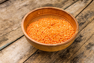 Raw lentil in bowl on wooden background