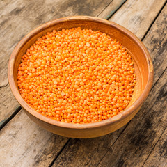 Raw lentil in bowl on wooden background