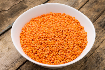 Raw lentil in bowl on wooden background