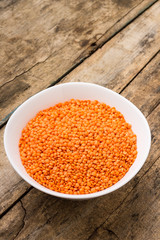 Raw lentil in bowl on wooden background