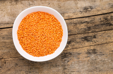 Raw lentil in bowl on wooden background