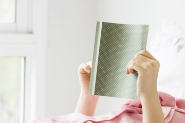 Young woman reading book on the bed