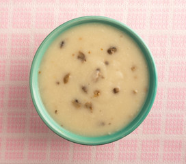 Bowl of cream of mushroom soup on pink and white table cloth