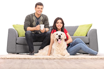Young couple sitting with a dog on a modern sofa