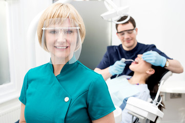 Male dentist with patient, in clinic.