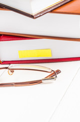 stack of books lying on white table glasses and a note
