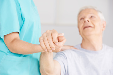 Krankenpflegerin hält Hand eines Senioren