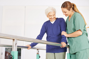 Physiotherapeutin hilft Seniorin auf Laufband