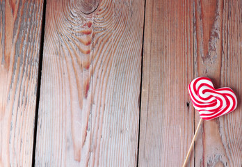 Heart shaped lollipop for Valentine's Day with wooden background