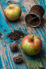 tea leaves and red apple on wooden background