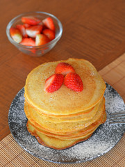 Stack of sweet pancakes with strawberry and icing sugar