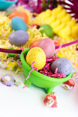 colored Easter eggs, yellow chicks and candy in a basket