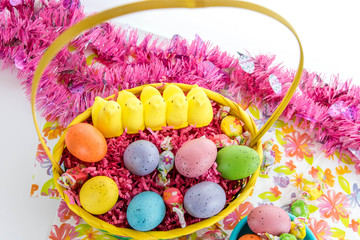 colored Easter eggs, yellow chicks and candy in a basket