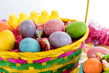 colored Easter eggs, yellow chicks and candy in a basket