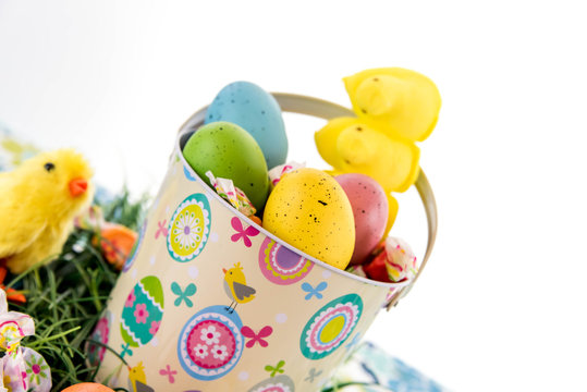 colored Easter eggs, yellow chicks, candy in a basket on grass