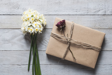 White narcissus flowers and present on wooden background