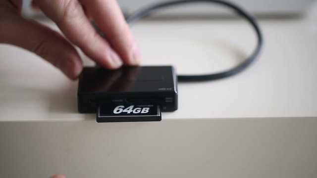 Hand inserting compact flash 64Gb in memory card reader