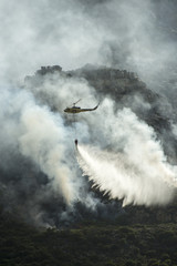 Fire fighting helicopter dropping water on a fire