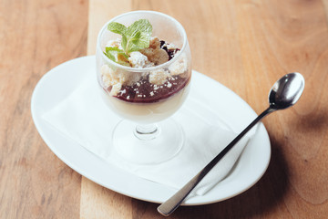 Panna cotta in Glas auf Teller mit Löffel // Ansicht von vorne