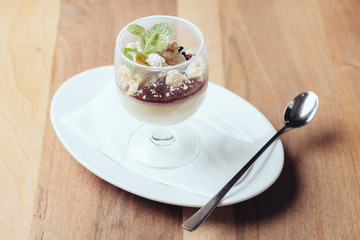 Panna cotta in Glas auf Teller mit Löffel // Ansicht von vorne
