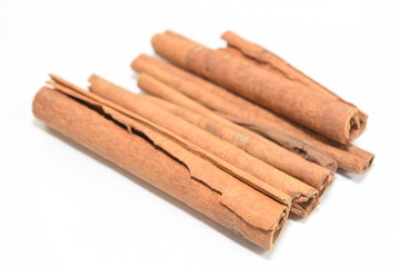 Cinnamon sticks stacked on white background.