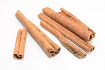 Cinnamon sticks stacked on white background.