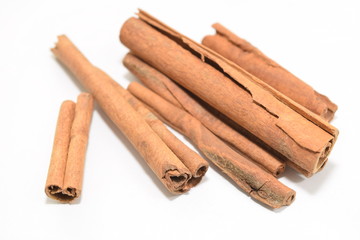 Cinnamon sticks stacked on white background.