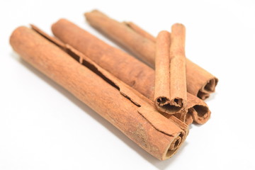 Cinnamon sticks stacked on white background.