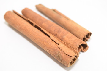 Cinnamon sticks stacked on white background.