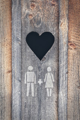 Heart cut out the wood with painted symbol of man and woman