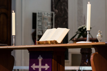 Open Bible and candles on the altar of a church