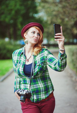 Hipster redhead woman in hat taking picture of herself
