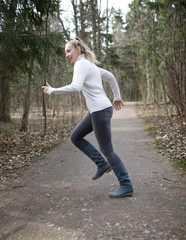 The woman runs on the track in the spring wood