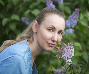Fototapeta premium Portrait of the young woman near the blossoming lilac