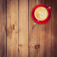 red cup and latte coffee on wood table with space.