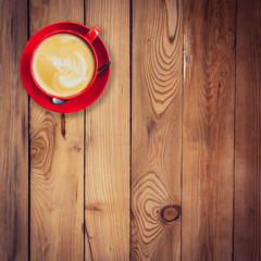 red cup and latte coffee on wood table with space.