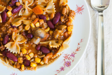 Chili con carne with pasta in plate, top view