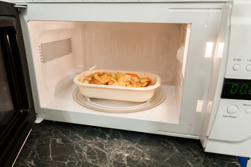 View of open microwave oven with delivery service food inside - 79973538