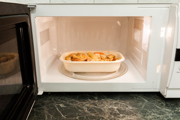 View of open microwave oven with delivery service food inside