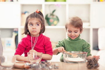 Obraz na płótnie Canvas Cute little girl and boy learning how to bake cookies