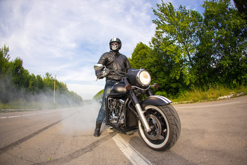 Fototapeta na wymiar biker staying with unknown big chopper bike on road with smoke o