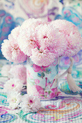 pink flowers in a mug on a beautiful tablecloth.