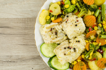 Cod fish on plate with vegetables