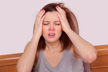 woman with red nose and suffering from terrible headache in bed