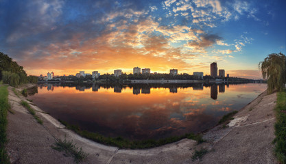 Summer sunset in the city. Reflection on the river.
