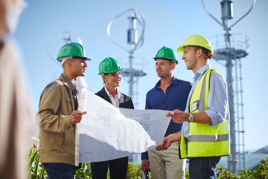 Business partners looking at wind turbine schematics with engineer