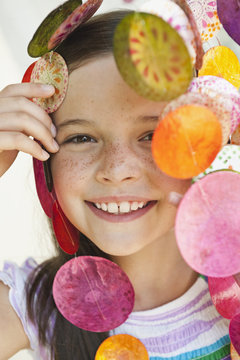 Germany, Bavaria, Girl looking through decorative sea shells wind chime