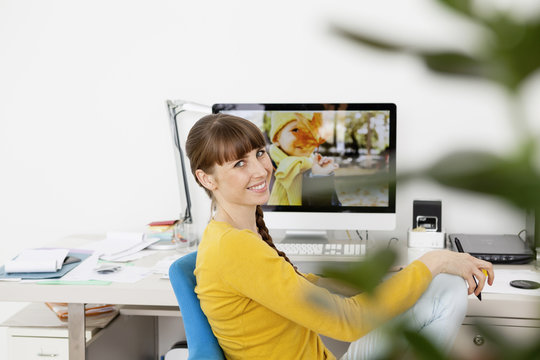 Woman at desk with photo oy boy on computer screen