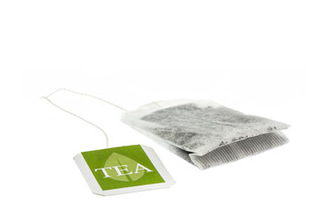 Tea paper sachet with green label isolated on white background
